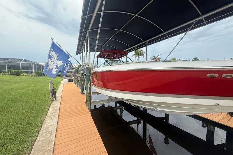  Yacht Photos Pics Red 2007 Cobalt 343 boat docked under canopy with flag, near green lawn.