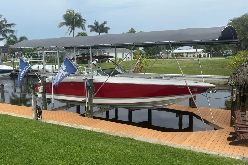  Yacht Photos Pics Red 2007 Cobalt 343 boat docked under canopy, surrounded by lush greenery and palm trees.