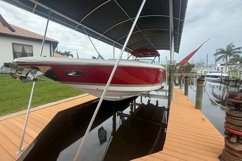  Yacht Photos Pics 2007 Cobalt 343 boat in red, docked under a canopy by a waterfront home.