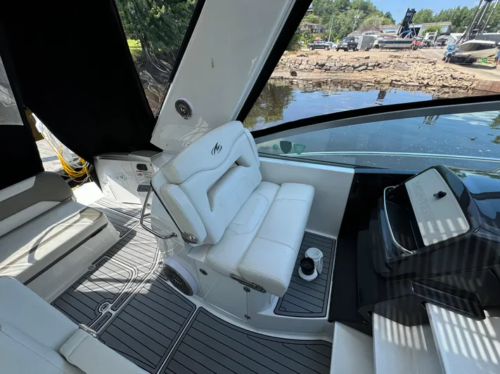  Yacht Photos Pics 2019 Monterey 335 SY boat interior with white seating and sleek dashboard, docked by a scenic shoreline.
