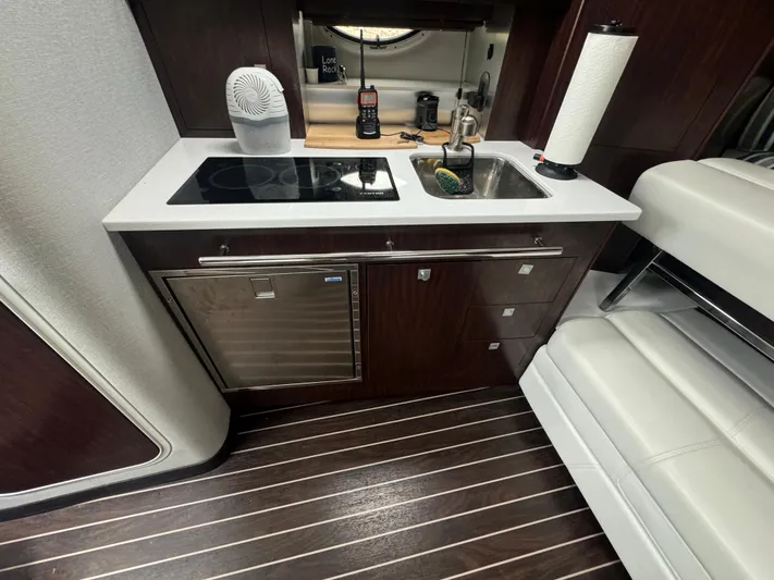  Yacht Photos Pics 2019 Monterey 335 SY yacht interior kitchen with stove, sink, and dark wood cabinetry.