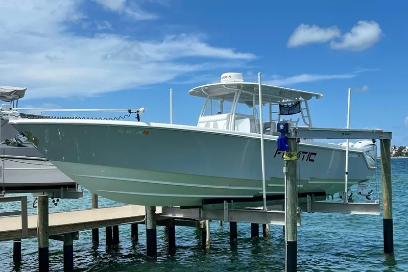  Yacht Photos Pics 2023 Contender 39 ST boat docked on a lift over clear blue water.