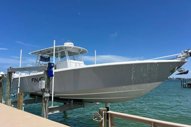  Yacht Photos Pics 2023 Contender 39 ST boat on lift, docked by clear blue water.