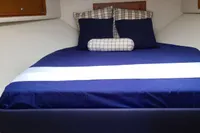Cabin interior of 2011 Cabo Express 40 with blue bedding and wooden cabinets.