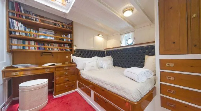 Puritan Yacht Photos Pics Luxurious 1931 schooner cabin with cozy bed, wooden desk, and bookshelf.