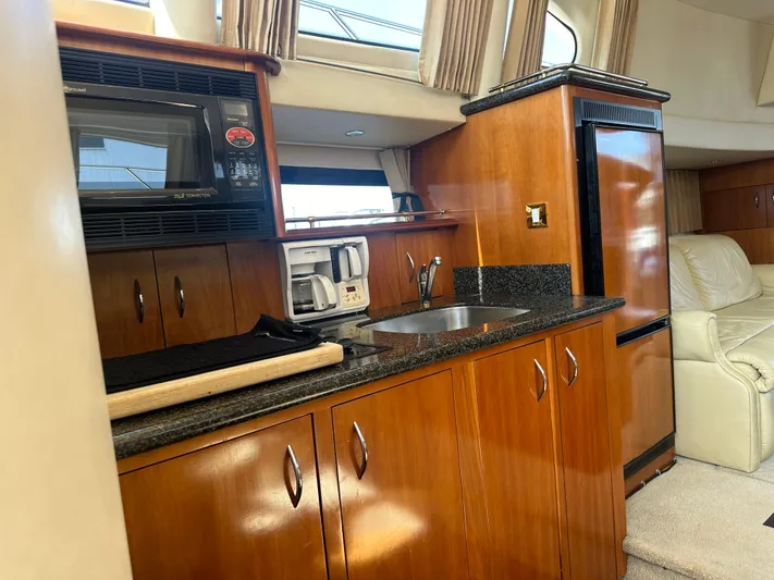  Yacht Photos Pics 2004 Carver 420 Mariner yacht interior with kitchenette, featuring wood cabinets and modern appliances.