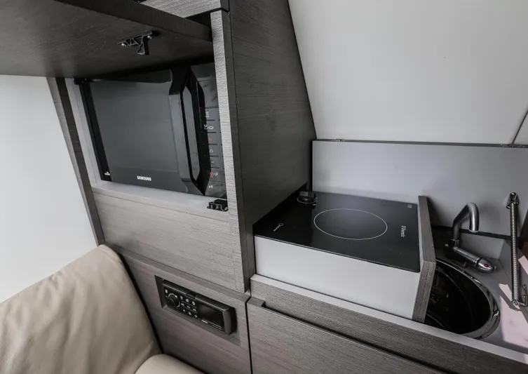  Yacht Photos Pics Compact kitchen area in a 2016 Wider 32, featuring a microwave, induction cooktop, and sink.