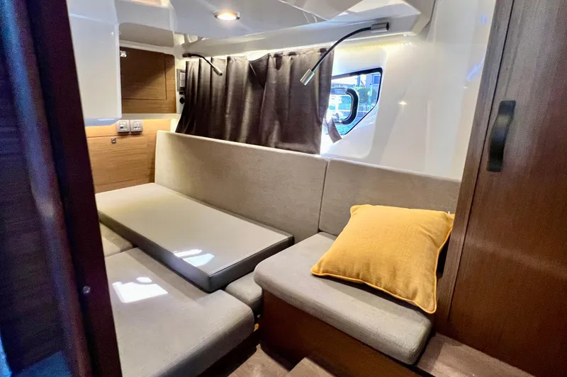  Yacht Photos Pics 2024 Beneteau Antares 11 interior with cozy seating, window, and yellow cushion.