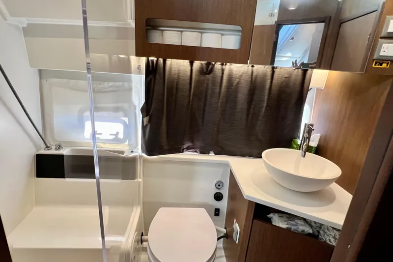  Yacht Photos Pics 2024 Beneteau Antares 11 bathroom with modern sink, toilet, and wooden cabinetry.