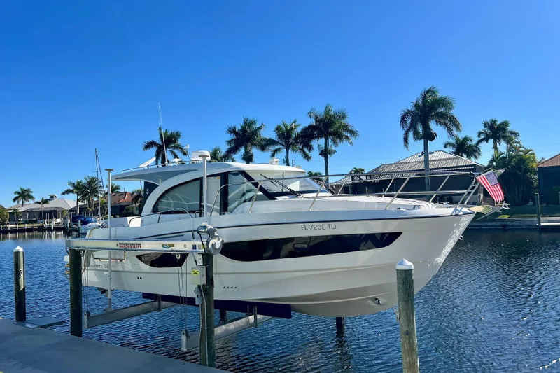  Yacht Photos Pics 2024 Beneteau Antares 11 yacht docked by palm trees under clear blue sky.