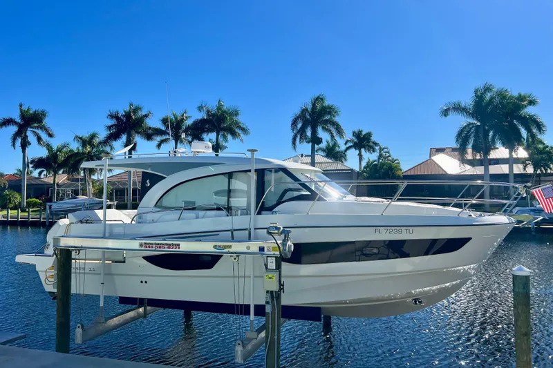  Yacht Photos Pics 2024 Beneteau Antares 11 boat docked by palm trees under clear blue sky.