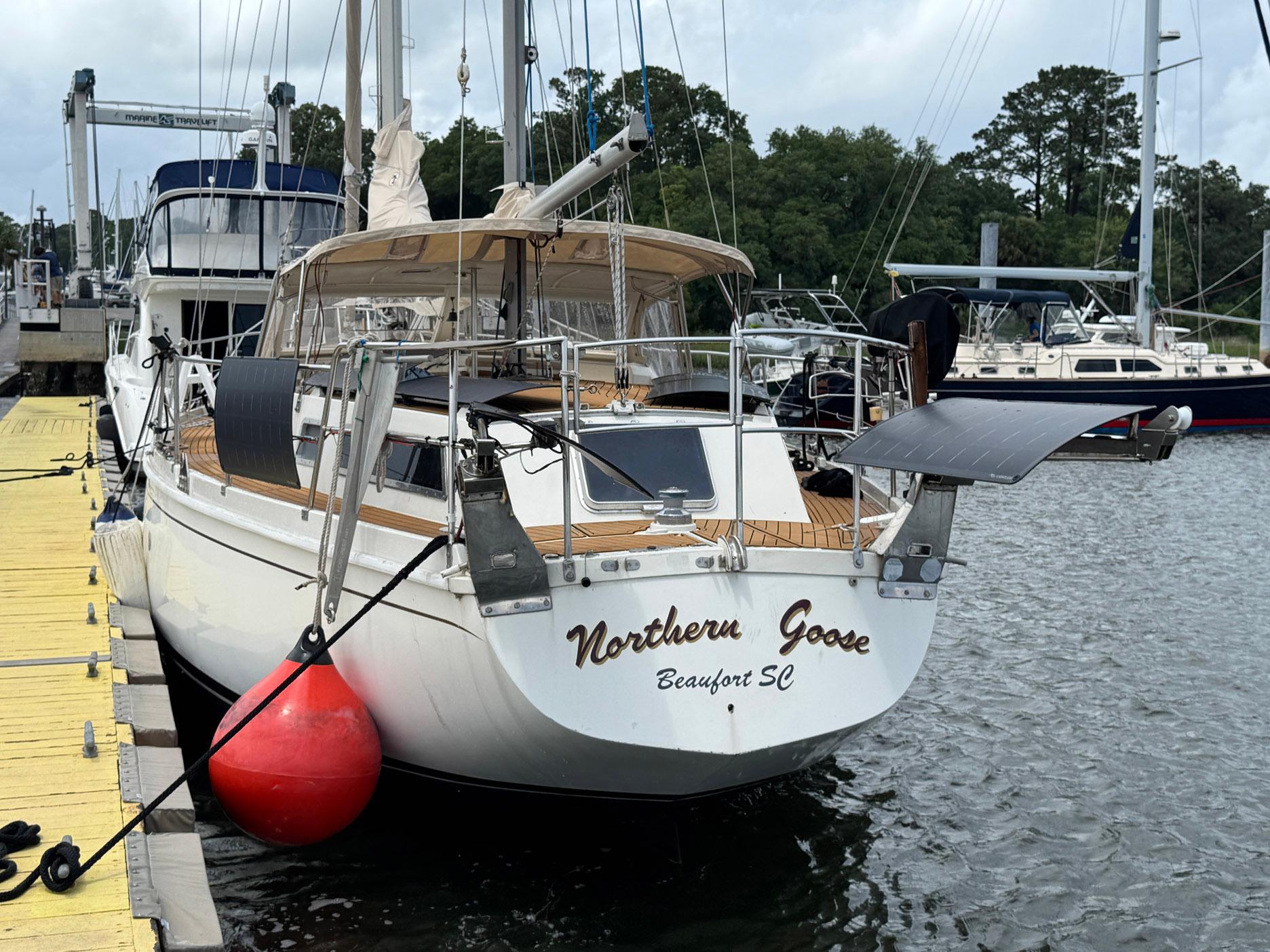 1980 Amel Mango 52 sailboat docked, featuring solar panels and wooden deck.
