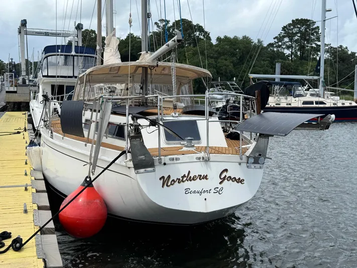 Northern Goose Yacht Photos Pics 1980 Amel Mango 52 sailboat docked, featuring solar panels and wooden deck.