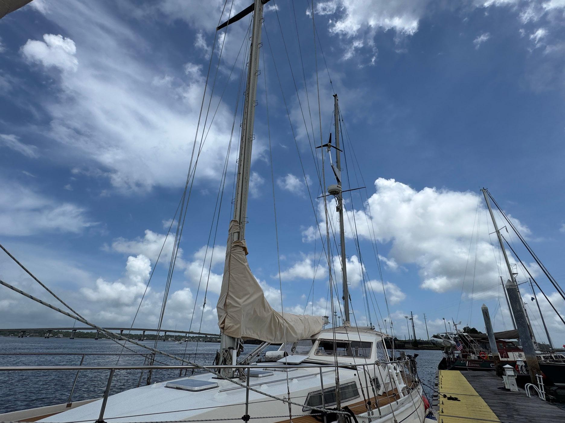 1980 Amel Mango 52 sailboat docked under a partly cloudy sky.