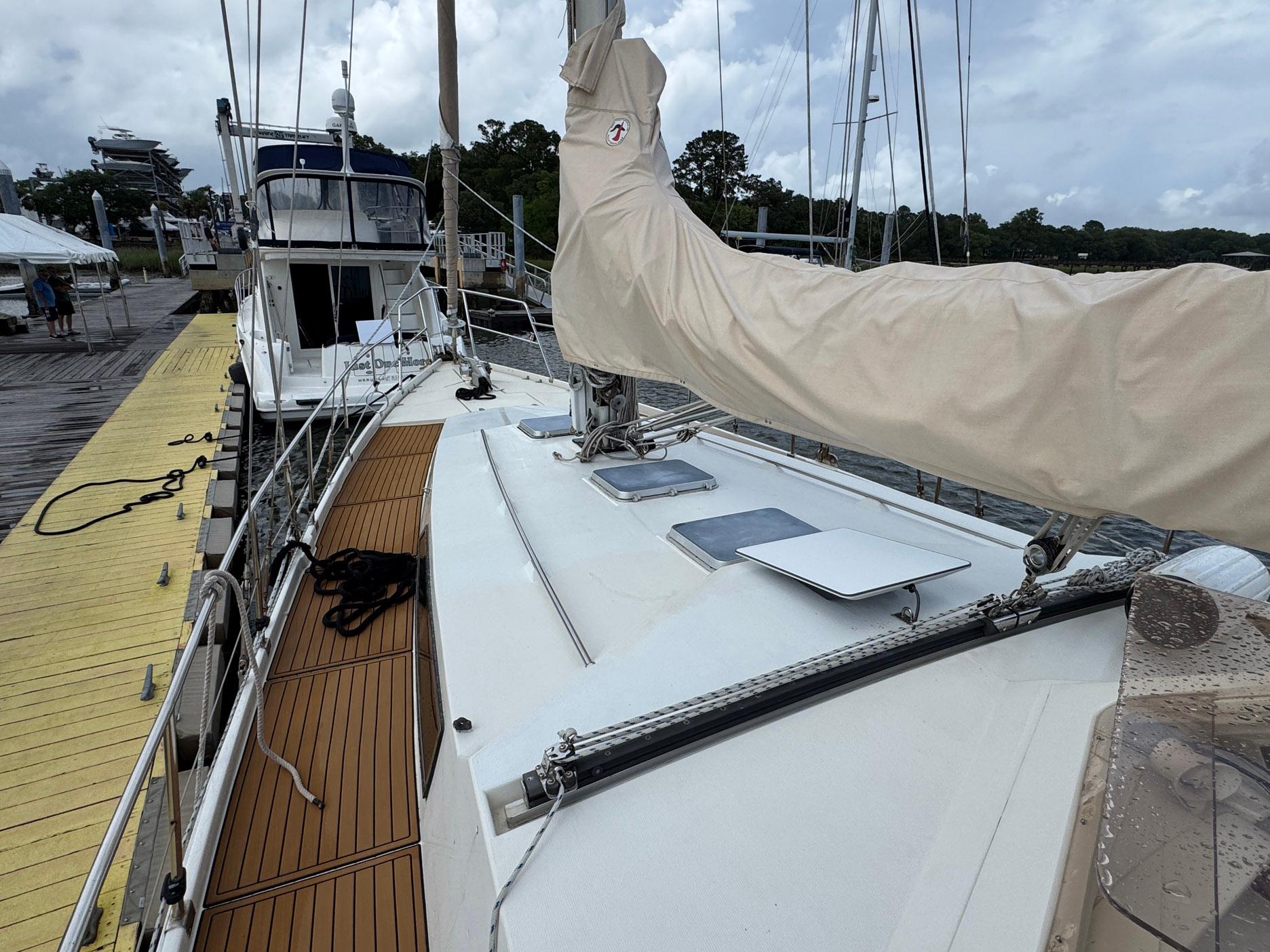 1980 Amel Mango 52 sailboat docked at marina, featuring teak deck and covered sails.