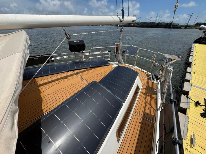Northern Goose Yacht Photos Pics 1980 Amel Mango 52 sailboat with solar panels on deck, docked by the water.