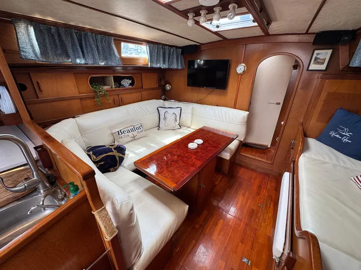 Northern Goose Yacht Photos Pics Cozy interior of 1980 Amel Mango 52 yacht with wood accents and white seating.