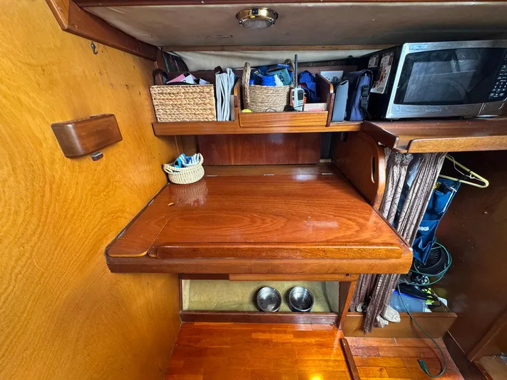 Northern Goose Yacht Photos Pics Interior of 1980 Amel Mango 52 yacht with wooden desk, storage, and microwave.