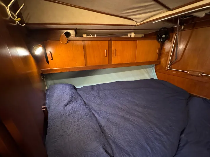 Northern Goose Yacht Photos Pics Cozy cabin interior of 1980 Amel Mango 52 sailboat with wooden cabinets and blue bedding.