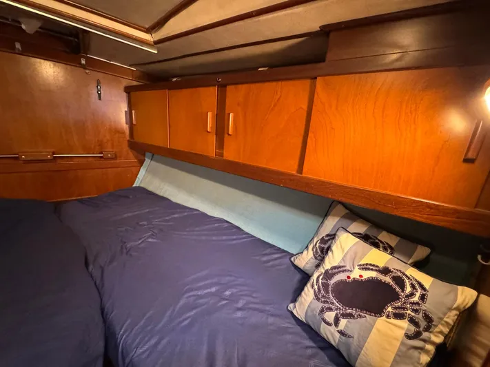 Northern Goose Yacht Photos Pics Cozy cabin interior of 1980 Amel Mango 52 sailboat with wooden cabinets and nautical-themed pillows.
