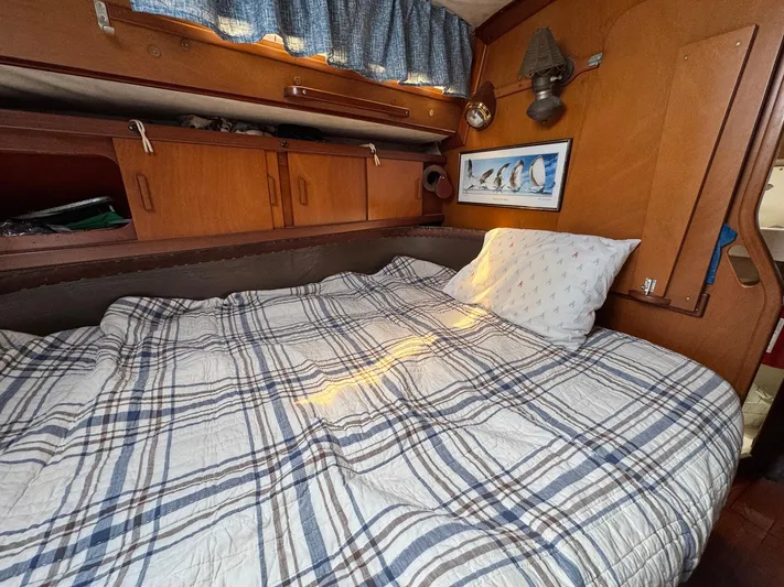 Northern Goose Yacht Photos Pics Cozy cabin interior of 1980 Amel Mango 52 sailboat with plaid bedding and wooden storage.
