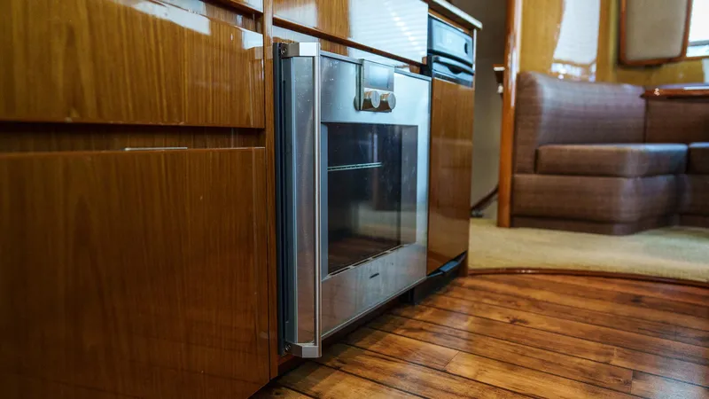 Benedetta Yacht Photos Pics Modern kitchen interior on 2012 Viking 70 Enclosed Bridge yacht, featuring wood cabinetry and stainless steel oven.