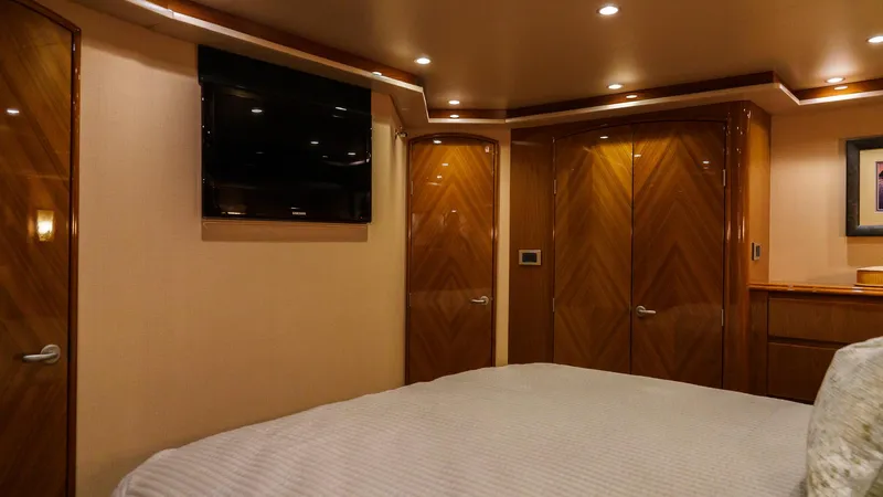 Benedetta Yacht Photos Pics Luxurious bedroom interior of 2012 Viking 70 Enclosed Bridge yacht with wood paneling and TV.