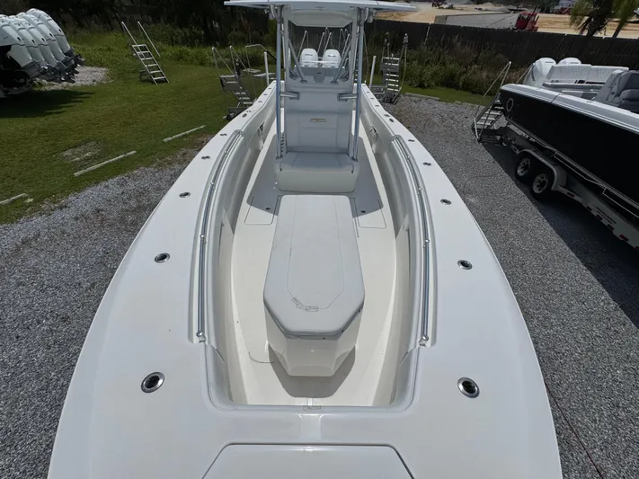  Yacht Photos Pics 2017 Invincible 33 Open Fisherman boat, white deck, parked on gravel, surrounded by greenery.