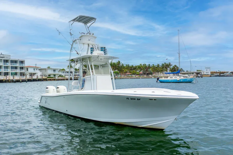  Yacht Photos Pics 2018 Ocean Runner 29 boat on water, with coastal buildings and palm trees in background.