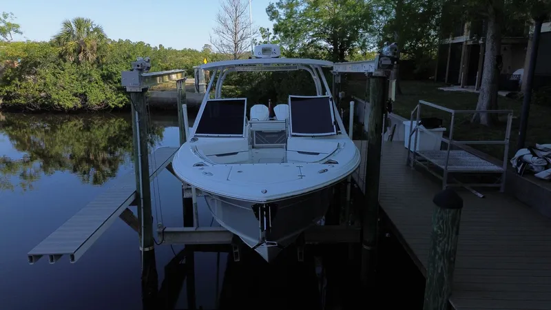  Yacht Photos Pics 2023 Blackfin 252 DC boat docked on a lift by a serene waterway.