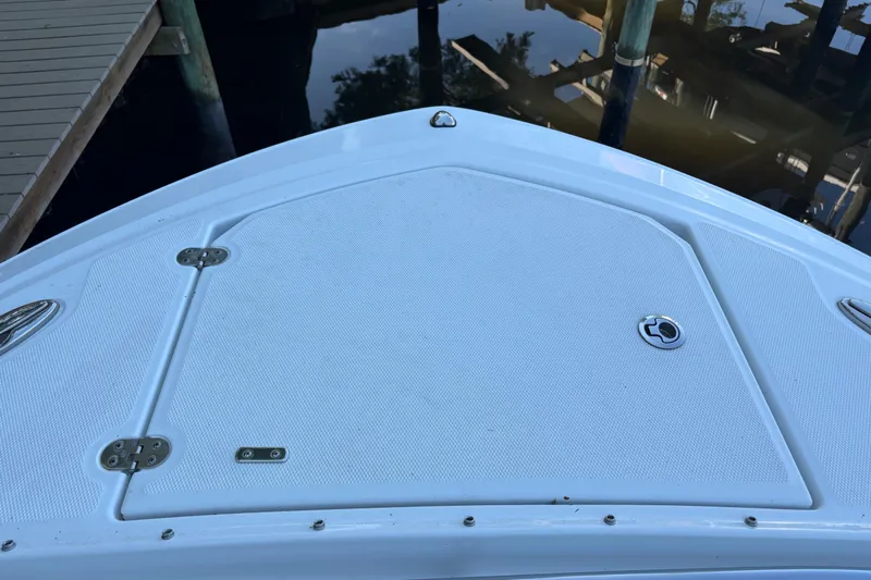  Yacht Photos Pics 2023 Blackfin 252 DC boat deck, docked by wooden pier, calm water reflection.