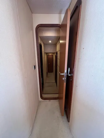 Amia Yacht Photos Pics Narrow hallway inside a 2006 Ferretti Yachts 731, featuring wooden doors and soft lighting.