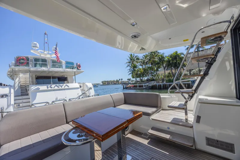 Aura Yacht Photos Pics Luxury yacht deck with seating area, Prestige 520, 2018 model, docked near palm trees.