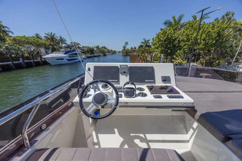 Aura Yacht Photos Pics Prestige 520 yacht helm, 2018 model, on a sunny canal with lush greenery.