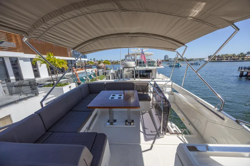 Aura Yacht Photos Pics Flybridge of 2018 Prestige 520 yacht with seating and table, docked by waterfront homes.