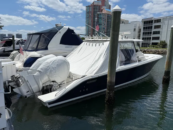  Yacht Photos Pics 2022 Pursuit S 358 Sport boat docked in marina, covered engines, urban backdrop.