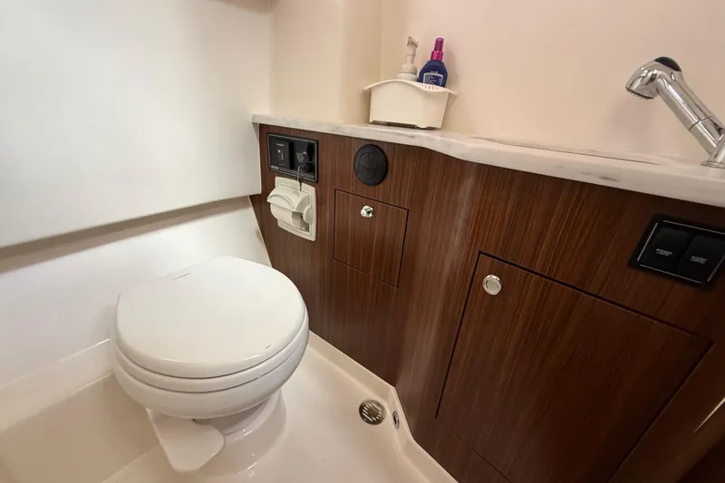  Yacht Photos Pics 2022 Pursuit S 358 Sport boat bathroom with modern fixtures and wood cabinetry.