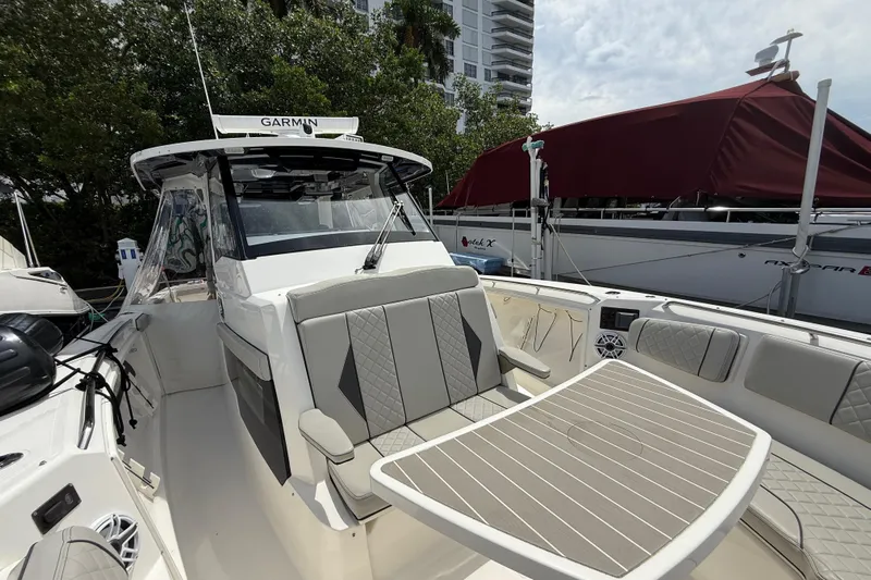  Yacht Photos Pics 2022 Pursuit S 358 Sport boat with seating and table, docked near other vessels.