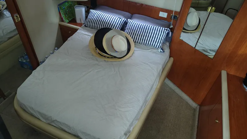 Spectre Yacht Photos Pics Cozy bedroom in 2001 Sea Ray 420 Aft Cabin with hats on bed.
