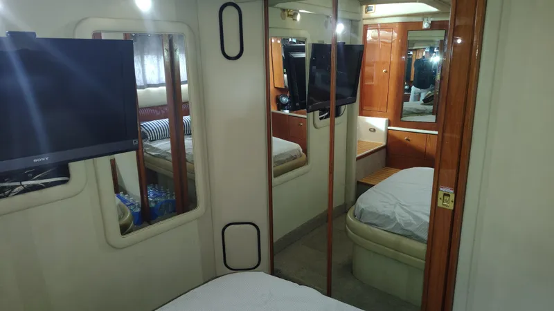 Spectre Yacht Photos Pics Interior of 2001 Sea Ray 420 Aft Cabin with mirrors, TV, and wooden cabinetry.