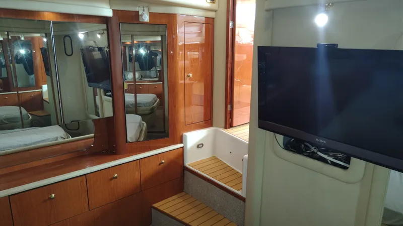 Spectre Yacht Photos Pics 2001 Sea Ray 420 Aft Cabin interior with wood cabinetry, mirrors, and a mounted TV.