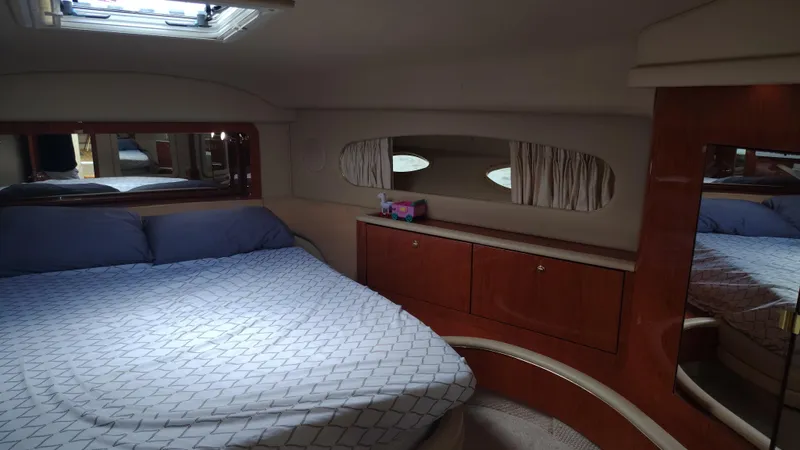 Spectre Yacht Photos Pics Interior of 2001 Sea Ray 420 Aft Cabin with bed, wooden cabinets, and porthole windows.