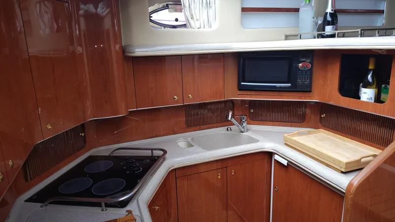 Spectre Yacht Photos Pics 2001 Sea Ray 420 Aft Cabin kitchen with stove, sink, microwave, and wooden cabinetry.