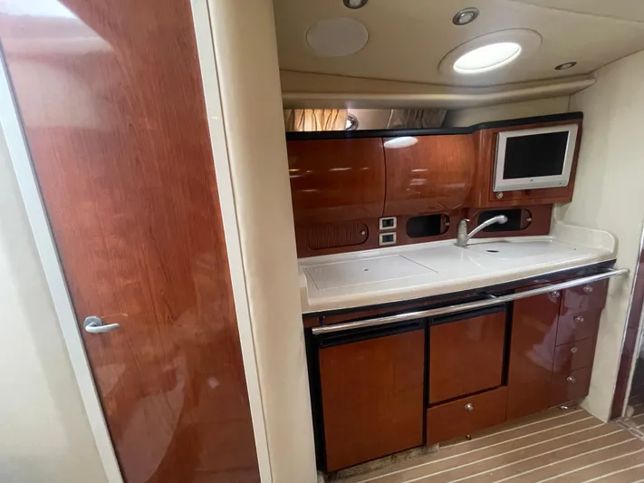  Yacht Photos Pics 2004 Sea Ray 360 Sundancer interior kitchen with wood cabinetry, sink, and built-in TV.