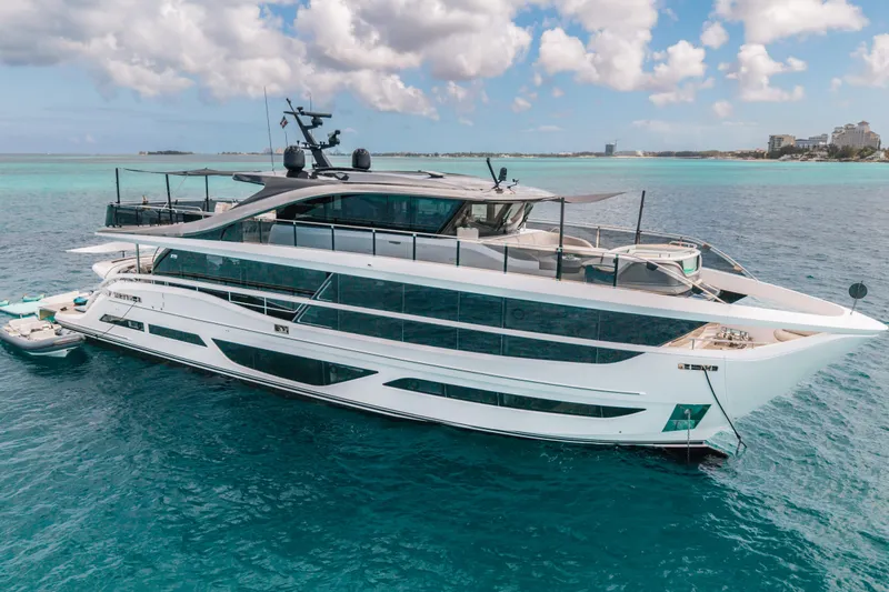 Gemini Yacht Photos Pics Luxurious 2023 Princess X95 yacht cruising in clear blue waters under a partly cloudy sky.