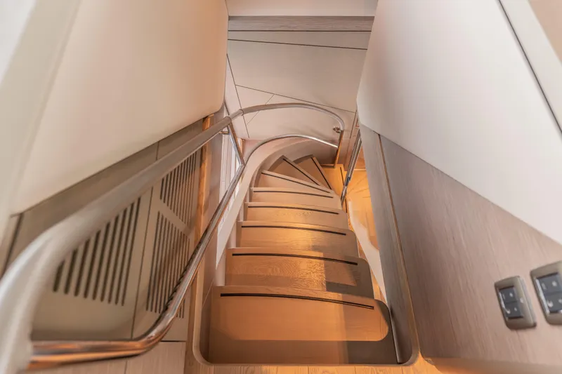 Gemini Yacht Photos Pics Curved wooden staircase inside 2023 Princess X95 yacht, featuring sleek modern design.