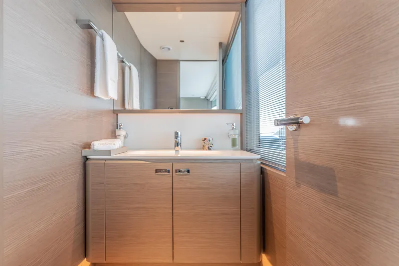 Gemini Yacht Photos Pics Luxurious bathroom interior on 2023 Princess X95 yacht, featuring modern sink and wooden cabinetry.