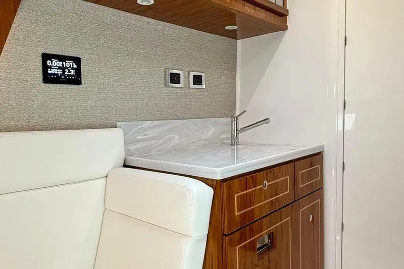  Yacht Photos Pics Interior of 2025 HCB 48 Campeon yacht featuring a sleek kitchenette with wood cabinetry.