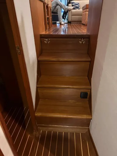 Gran Vida Yacht Photos Pics Wooden stairs inside a 1998 Ocean Yachts Super Sport, leading to a cozy seating area.