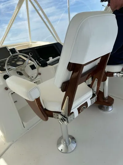 Gran Vida Yacht Photos Pics Captain's chair on 1998 Ocean Yachts Super Sport, featuring white upholstery and wooden accents.